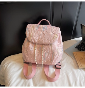 Detailed view of pink quilted backpack with colorful embroidery and drawstring closure