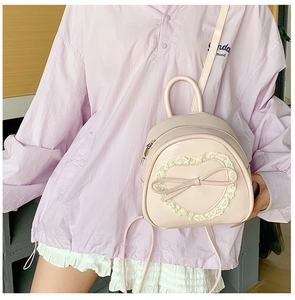 Détail d'un mini sac à dos rose clair avec dentelle en cœur et un nœud ruban élégant