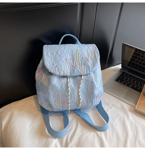 Detail of light blue backpack with colorful wave embroidery and textured letter patterns