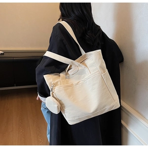 Detail of off-white canvas tote bag with mini coin purse on model in a cozy interior