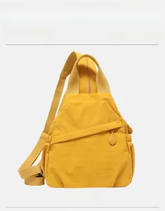 Detail of a bright yellow nylon chest bag featuring front zipper and woven shoulder strap