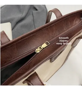 Detail of smooth gold-tone zipper and contrast faux leather texture on the tote bag