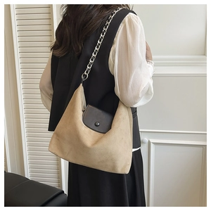 Close-up of khaki suede tote bag with silver chain strap and black magnetic flap detail