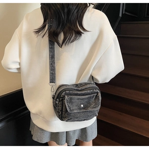 Detail view of retro denim crossbody bag with adjustable wide strap on model