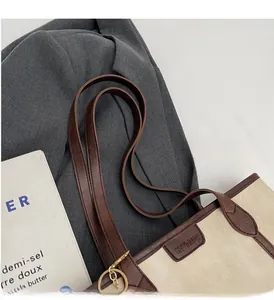Detail of canvas tote bag with brown lychee leather trim and long shoulder straps