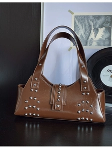 Vintage dark brown leather underarm bag with silver rivets on a retro wooden surface