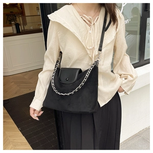 Close-up of a black matte tote bag featuring silver chain decor and leather flap