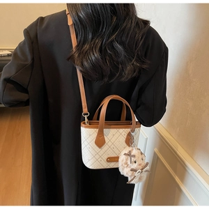 Detail of checkered tote bag with brown leather straps and plush bunny pendant charm
