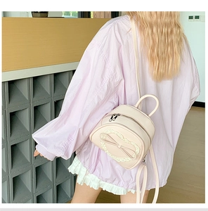Vue détaillée d'un mini sac à dos rose pâle avec dentelle et un nœud central élégant