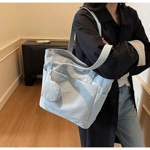 Light blue canvas tote bag detail showing large capacity side pockets and round coin purse