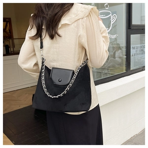 Detail of black suede and leather tote bag featuring stylish silver woven chain strap