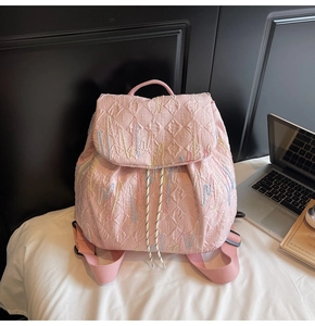 Detail view of pink quilted backpack with colorful embroidery and ripple stitch texture