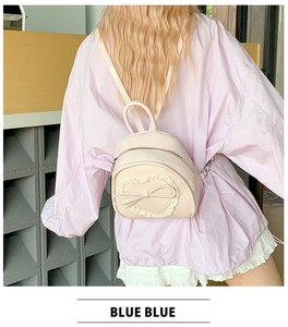 Détail d'un sac à dos rose clair avec dentelle, patch en forme de cœur et nœud