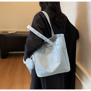 Detail of light blue canvas tote bag with side pocket and matching round coin purse charm