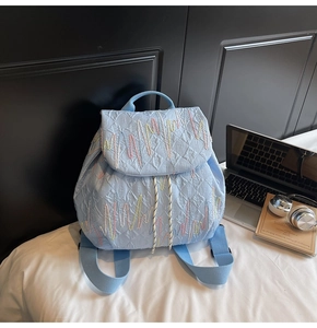 Close-up of light blue quilted backpack with wavy colorful embroidery and drawstring closure