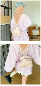 Détail d'un mini sac à dos rose clair avec bordure en dentelle cœur et nœud élégant