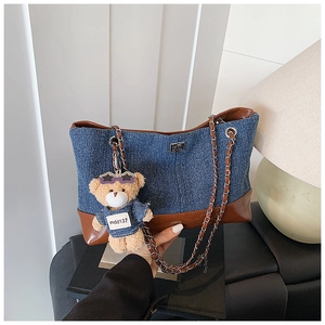 Detail of denim tote bag with leather trim, metal twist lock and cute bear charm