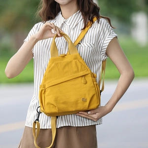 Detail of a bright yellow mini nylon backpack with adjustable straps and side drawstring pocket