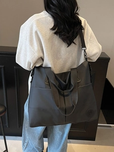 Black large capacity waterproof nylon backpack shown on a model in a minimalist setting