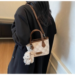 Detail of checkered tote bag with plush bunny charm and detachable leather strap