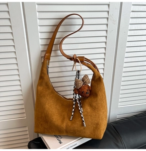 Close-up of brown suede hobo bag featuring vertical stitching and a cute bear charm