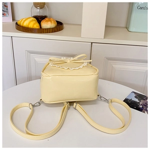 Vue détaillée des bretelles réglables et dentelle sur un mini sac à dos jaune crème