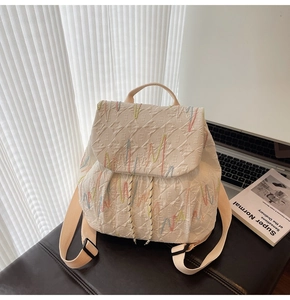 Detail of minimalist cream backpack showing colorful wave embroidery and jacquard texture