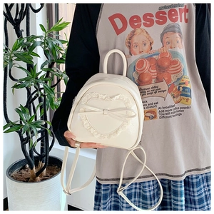 Détail du mini sac à dos crème avec applique en dentelle en cœur et nœud décoratif