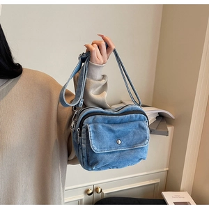 Classic blue denim crossbody bag with adjustable wide strap shown in a lifestyle setting