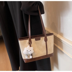 Detail of a two-tone tote bag with brown leather trim and a cute cloud charm accessory
