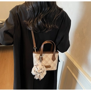 Detail of checkered mini tote bag with plush rabbit charm and gold logo plate