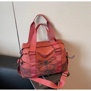 Vue détaillée du sac de voyage rouge brique avec poche latérale en filet et cordons avant