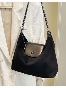 Minimalist black tote shoulder bag with chain strap on textured white blazer