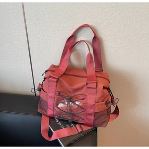 Détail du sac de voyage rouge brique avec cordons élastiques noirs et fenêtre transparente