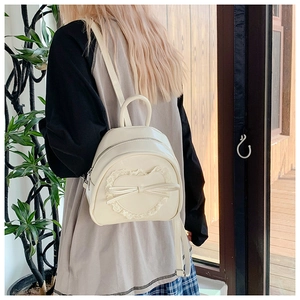 Détail du motif cœur en dentelle et nœud sur un mini sac à dos en similicuir crème