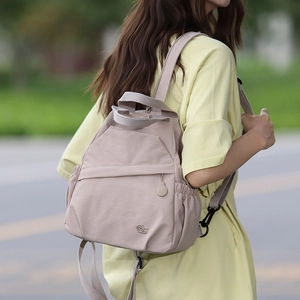 Detail view of pink nylon backpack with MS logo and adjustable straps in outdoor setting