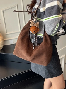 Retro dark brown suede crescent shoulder bag with a cute bear pendant on a model
