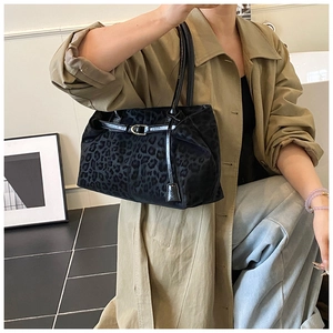 Dettaglio della borsa tote leopardata nera con fibbie su un trench coat beige