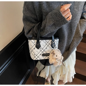 Detail of checkered mini tote bag featuring a cute plush bunny charm and branded metal tag