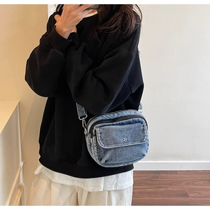 Detail view of light blue denim crossbody bag with adjustable strap on a model