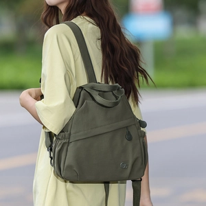 Detail of army green nylon backpack showing side pocket and circular metal logo