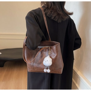 Detail of dark brown leather tote bag with vintage texture and white cloud charm