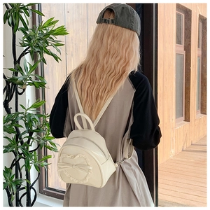 Détail d'un mini sac à dos crème avec dentelle en cœur et nœud au style doux et chic