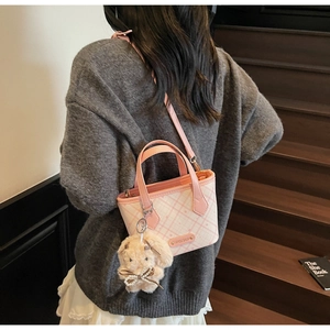 Pink checkered tote bag detail with cute white plush bunny charm and metal nameplate