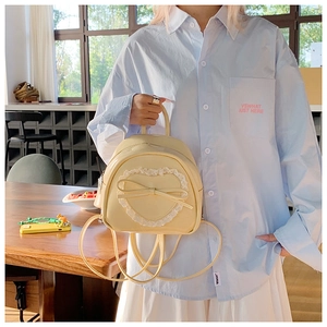 Détail du mini sac à dos crème avec motif cœur en dentelle et nœud élégant en cuir
