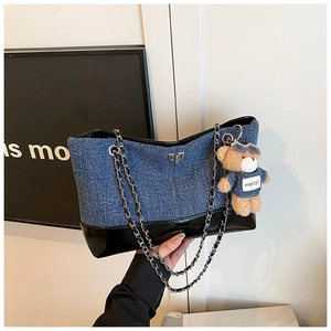 Detail of denim tote bag with black lacquer trim, silver chain, and cute bear charm