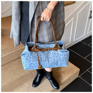 Dettaglio della borsa tote blu leopardata con manici marroni e cinturino con fibbia