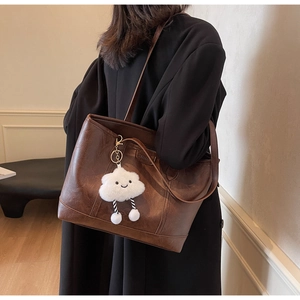 Detail of dark brown lychee grain tote bag with a cute white cloud plush charm