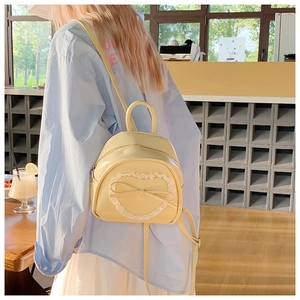 Vue détaillée du sac à dos en cuir jaune avec cœur en dentelle blanche et ornements