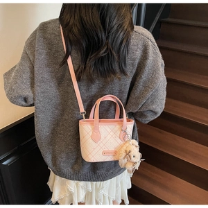 Pink and white checkered tote bag with plush rabbit charm worn by a model in casual setting